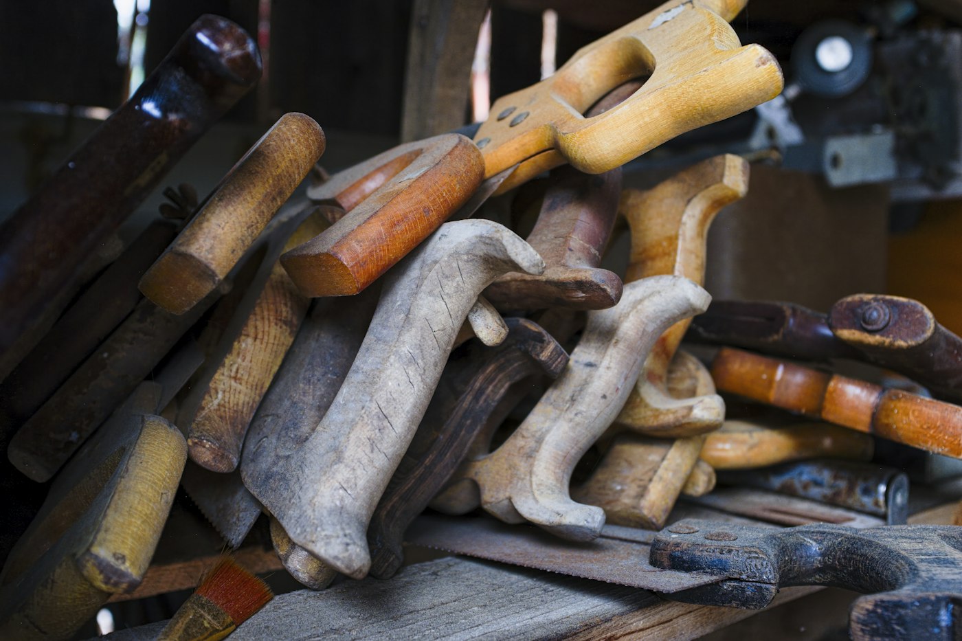 A pile of well-used hand saws and woodworking tools